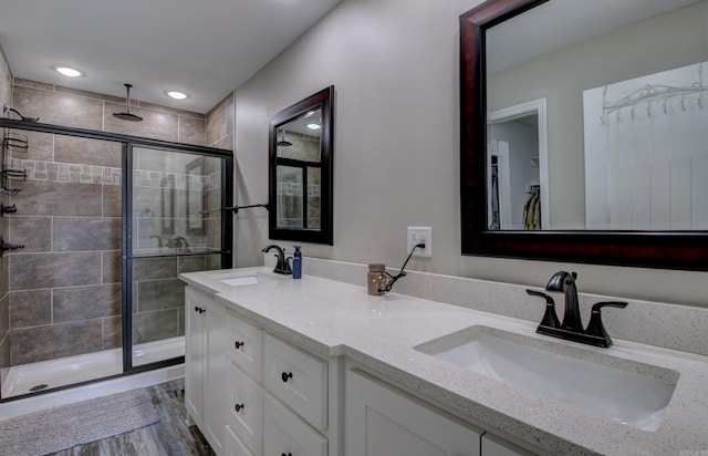 bathroom with hardwood / wood-style floors, vanity, and a shower with shower door