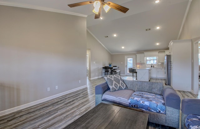 living room with crown molding, ceiling fan, wood-type flooring, and vaulted ceiling