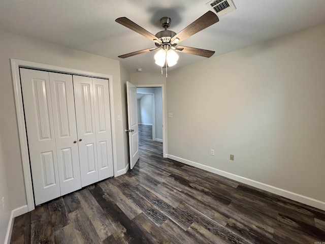 unfurnished bedroom with ceiling fan, dark hardwood / wood-style floors, and a closet