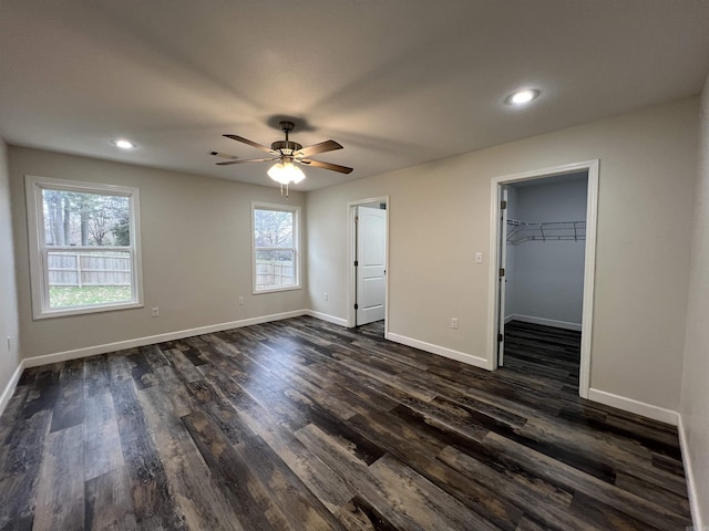 unfurnished bedroom featuring a closet, a walk in closet, dark hardwood / wood-style floors, and ceiling fan