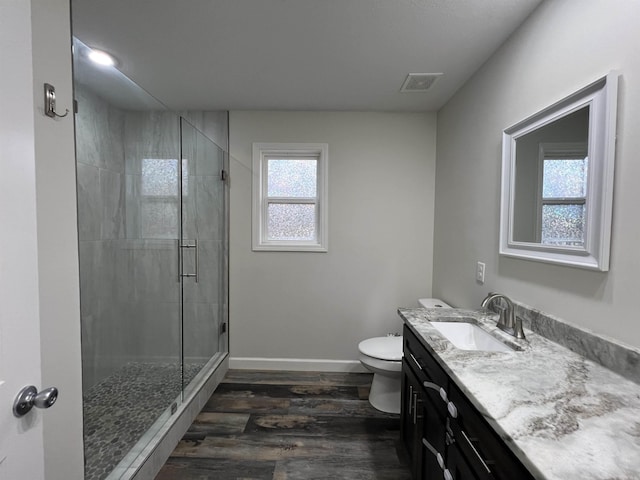 bathroom with hardwood / wood-style floors, vanity, toilet, and a shower with door