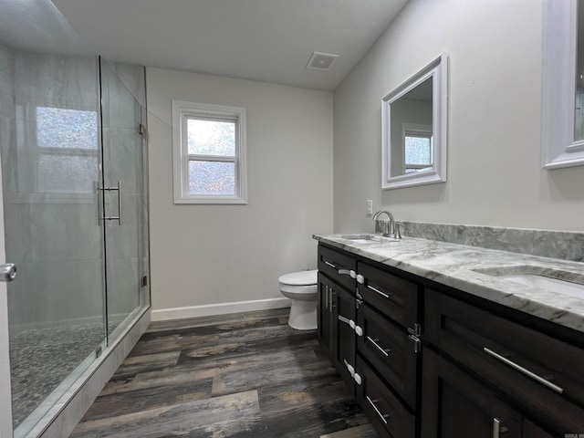 bathroom with wood-type flooring, vanity, toilet, and a shower with door