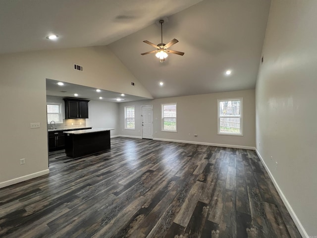 unfurnished living room featuring ceiling fan, dark hardwood / wood-style flooring, high vaulted ceiling, and sink