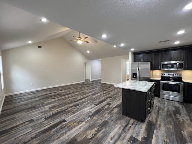 kitchen featuring dark hardwood / wood-style flooring, stainless steel appliances, ceiling fan, a center island, and lofted ceiling