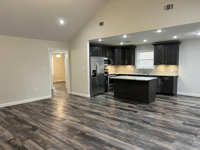 kitchen featuring stainless steel appliances, sink, high vaulted ceiling, a center island, and dark hardwood / wood-style floors