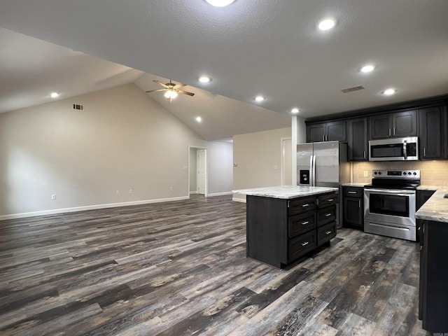 kitchen with dark hardwood / wood-style flooring, stainless steel appliances, ceiling fan, a center island, and lofted ceiling