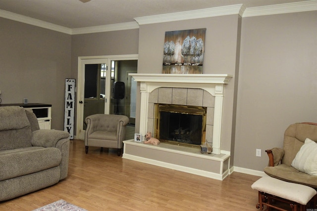 living room featuring light hardwood / wood-style floors, ornamental molding, and a tile fireplace