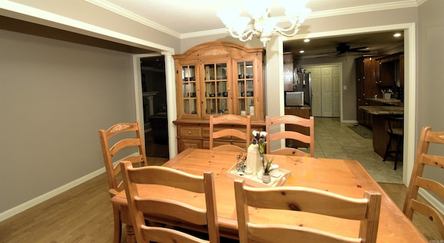 dining space with ceiling fan with notable chandelier, light wood-type flooring, ornate columns, and crown molding