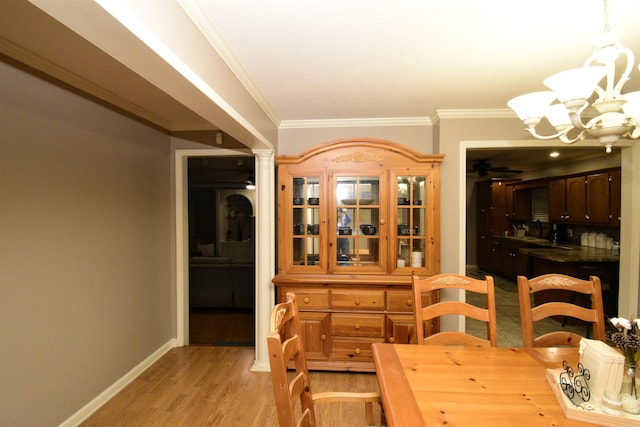 dining area featuring light hardwood / wood-style floors, ornate columns, crown molding, and a chandelier