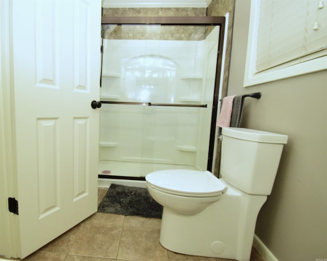 bathroom featuring tile patterned flooring, toilet, and a shower with door