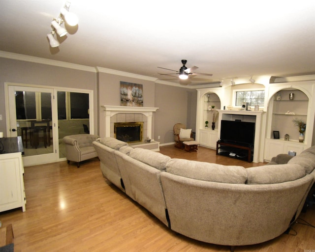 living room featuring a tiled fireplace, ceiling fan, hardwood / wood-style floors, and ornamental molding