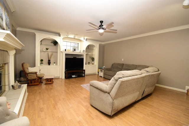 living room with crown molding, a fireplace, ceiling fan, and light hardwood / wood-style floors