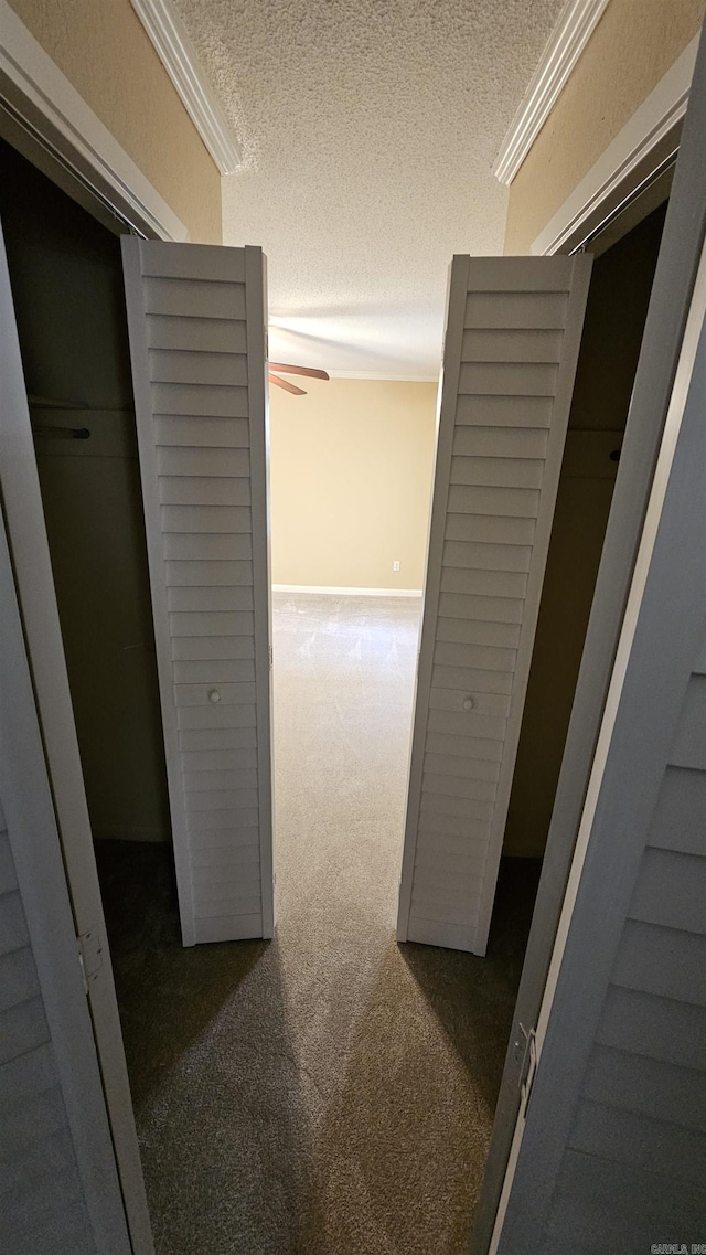 hallway featuring a textured ceiling and dark carpet