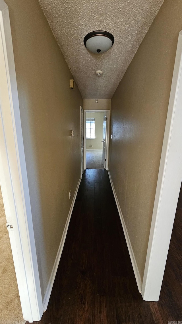 corridor with dark hardwood / wood-style floors and a textured ceiling