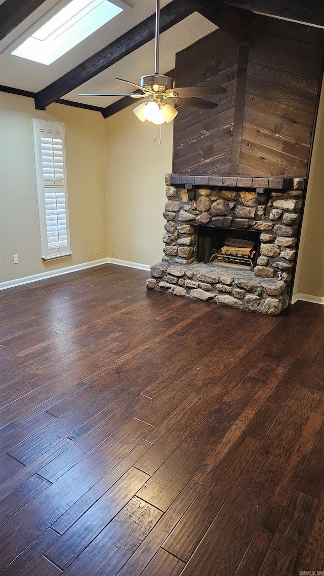 unfurnished living room featuring a fireplace, hardwood / wood-style flooring, lofted ceiling with skylight, and ceiling fan