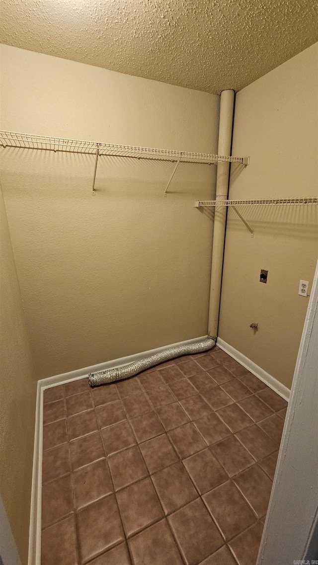 laundry area with a textured ceiling, dark tile patterned floors, and electric dryer hookup