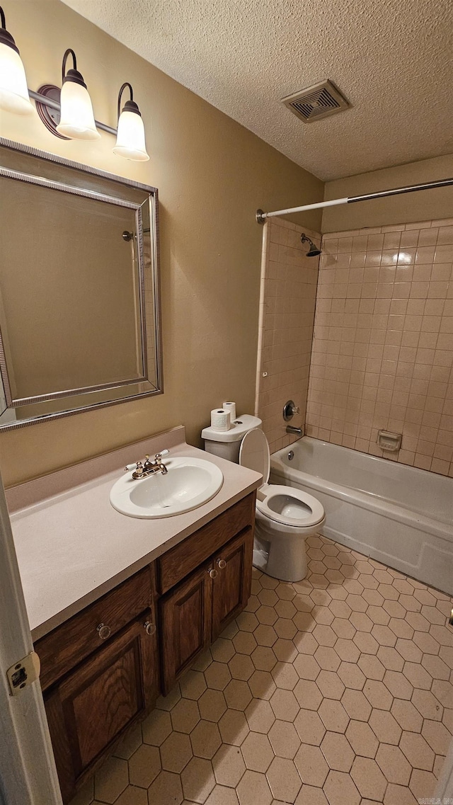 full bathroom with tiled shower / bath combo, tile patterned flooring, a textured ceiling, toilet, and vanity