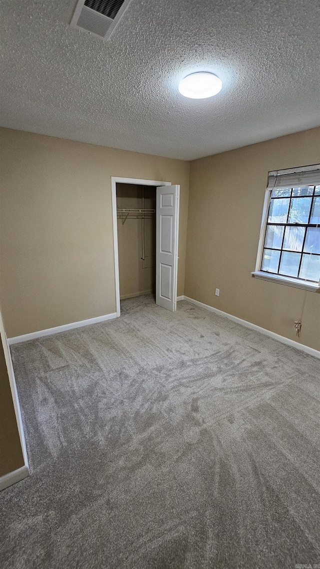 unfurnished bedroom with a closet, carpet floors, and a textured ceiling