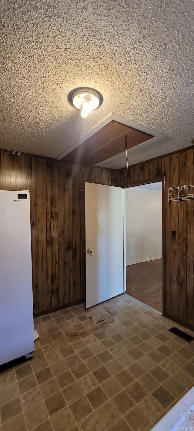 spare room featuring wood walls and a textured ceiling