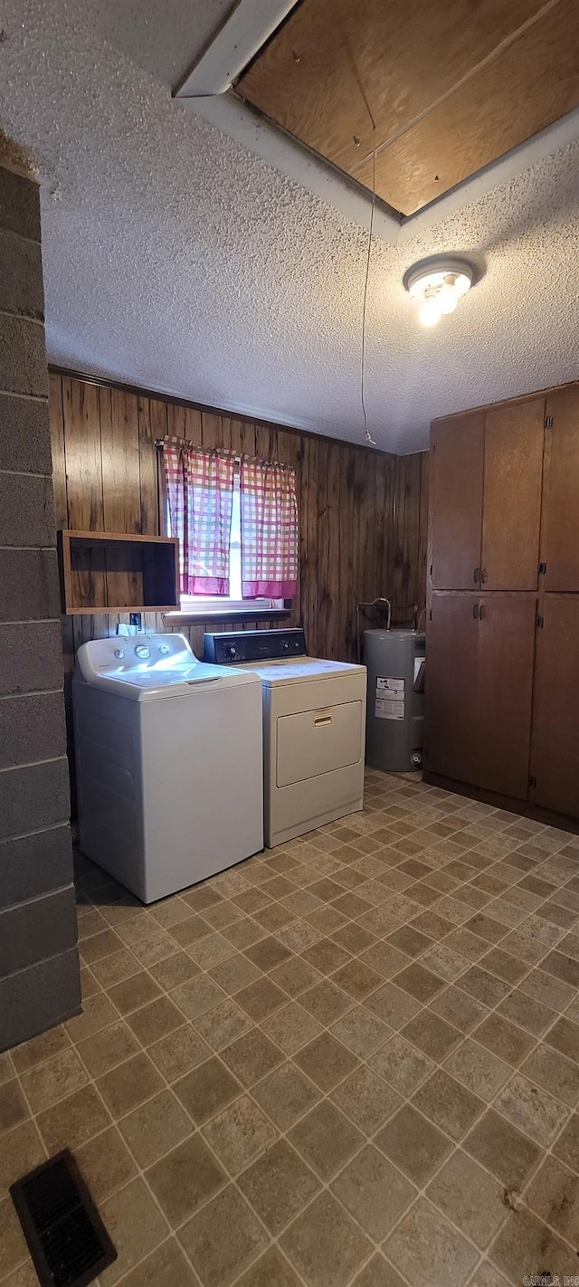 washroom featuring wood walls, water heater, and a textured ceiling