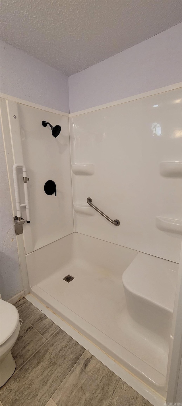 bathroom featuring hardwood / wood-style floors, toilet, a textured ceiling, and walk in shower