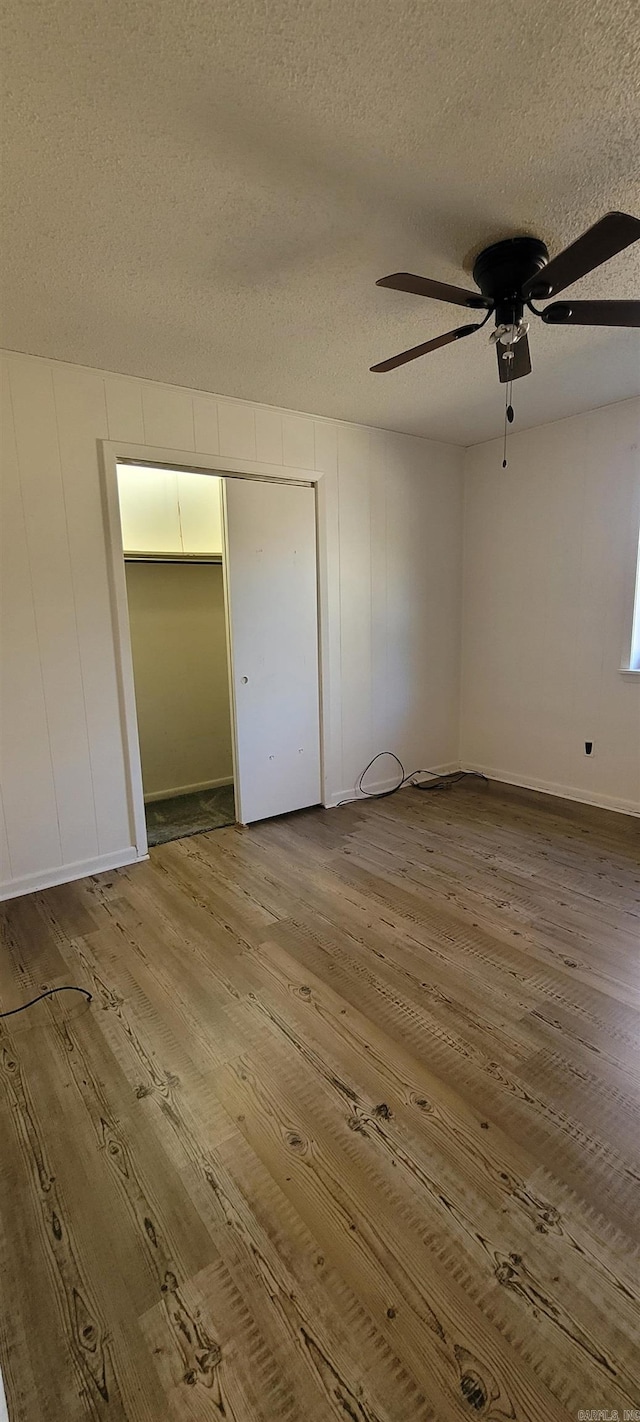 unfurnished bedroom with hardwood / wood-style floors, ceiling fan, a textured ceiling, and a closet