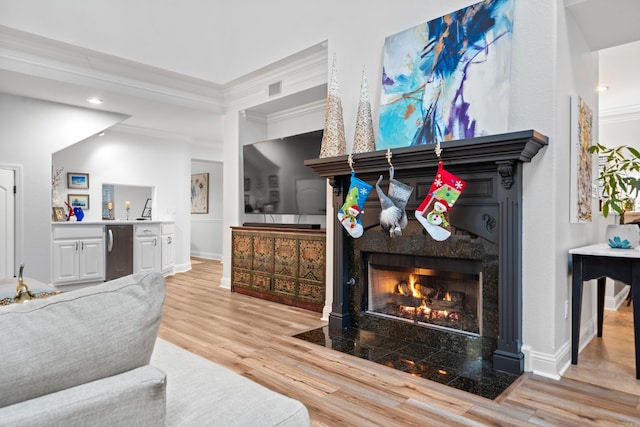 interior space featuring stainless steel refrigerator, a fireplace, hardwood / wood-style floors, and ornamental molding