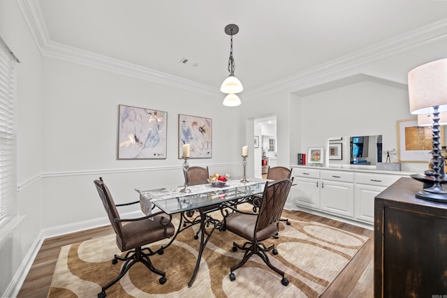 dining space featuring wood-type flooring and crown molding