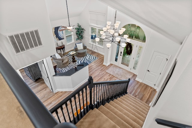 interior space with hardwood / wood-style floors, ceiling fan with notable chandelier, and high vaulted ceiling