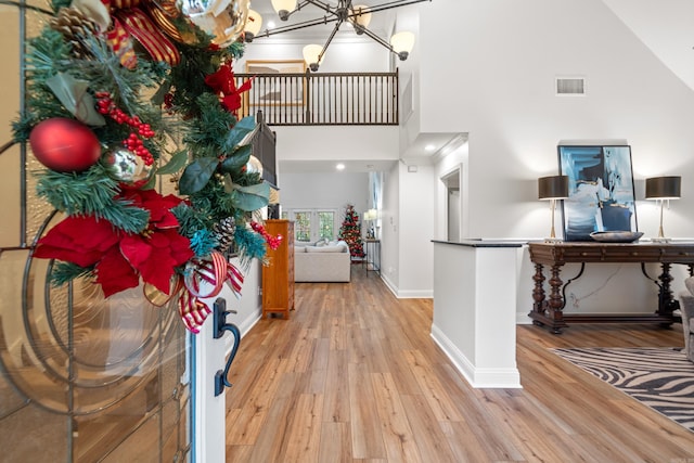 foyer entrance featuring a chandelier, light hardwood / wood-style floors, and high vaulted ceiling