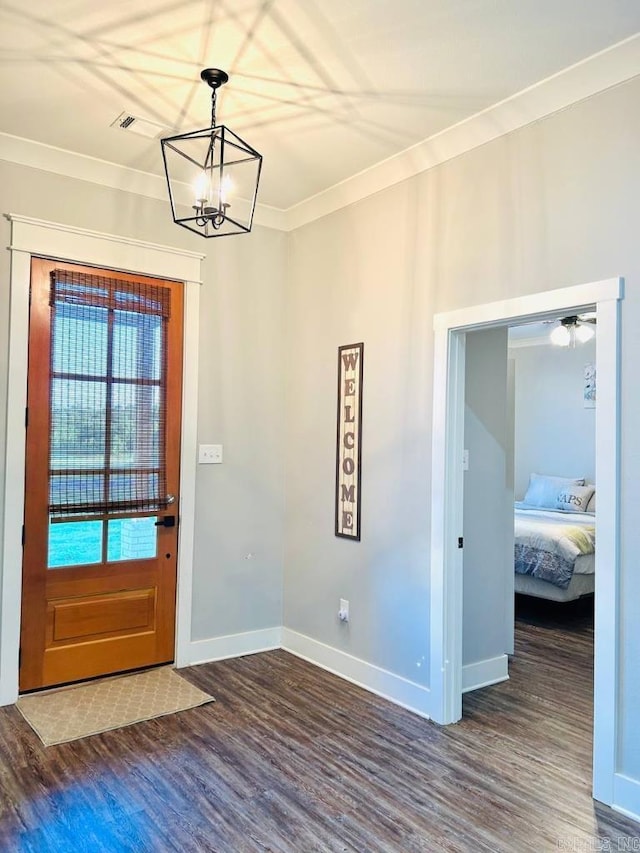 entryway featuring crown molding, dark hardwood / wood-style floors, and an inviting chandelier