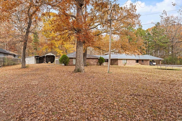 view of yard with a carport and a trampoline