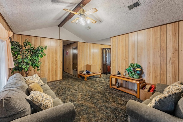 carpeted living room with wood walls, ceiling fan, lofted ceiling with beams, and a textured ceiling