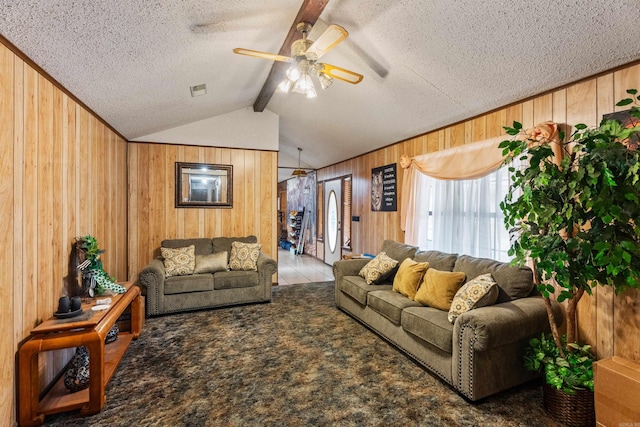 living room featuring carpet, lofted ceiling with beams, ceiling fan, and wood walls