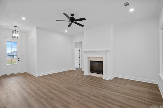 unfurnished living room featuring ornamental molding, ceiling fan with notable chandelier, and hardwood / wood-style flooring