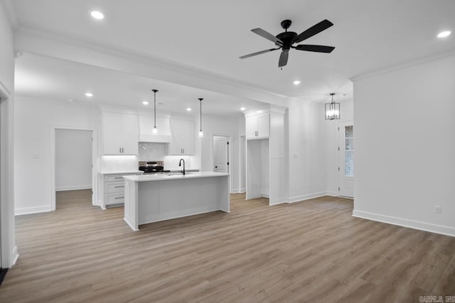 kitchen featuring pendant lighting, a center island with sink, white cabinetry, and light hardwood / wood-style floors