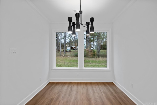 unfurnished dining area featuring hardwood / wood-style flooring, a notable chandelier, and crown molding