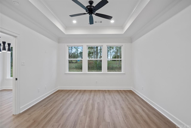 unfurnished room with a tray ceiling, crown molding, and light hardwood / wood-style flooring