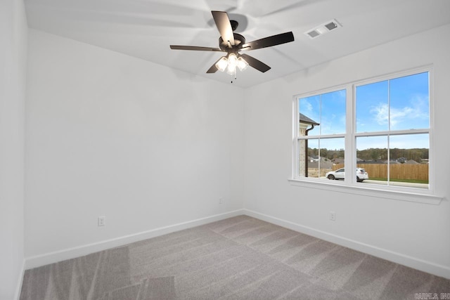 carpeted spare room featuring a wealth of natural light and ceiling fan