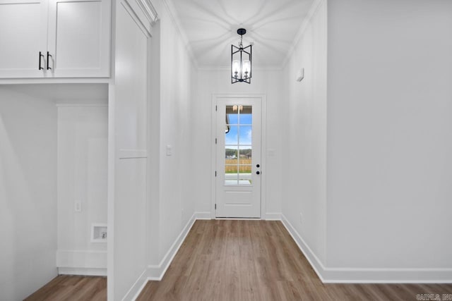 doorway to outside with crown molding, light hardwood / wood-style floors, and a notable chandelier