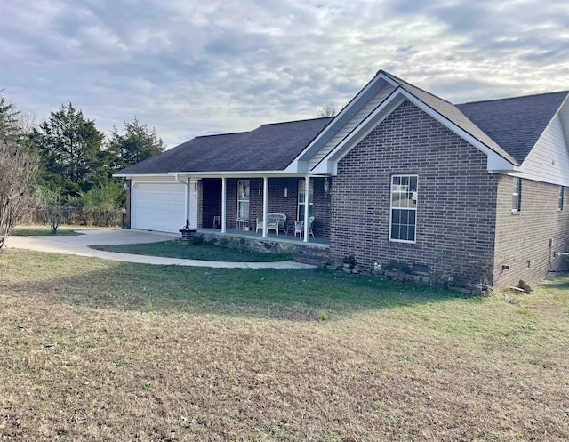 view of front of property featuring covered porch, a garage, and a front yard