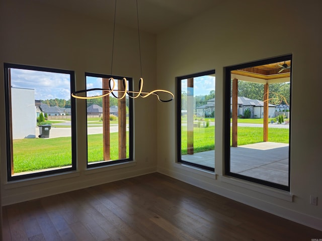 unfurnished dining area with a notable chandelier, dark hardwood / wood-style floors, and a healthy amount of sunlight