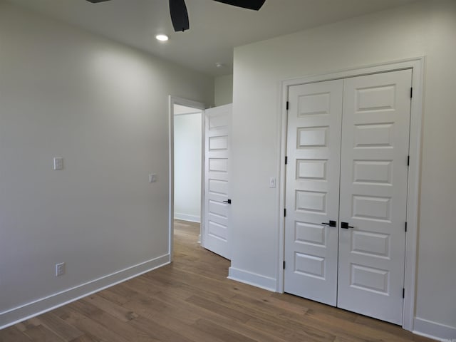 unfurnished bedroom with ceiling fan, a closet, and hardwood / wood-style flooring