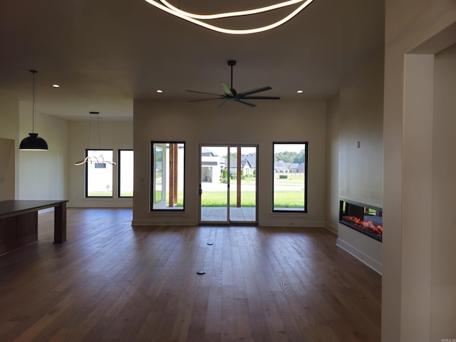 unfurnished living room featuring ceiling fan and dark wood-type flooring