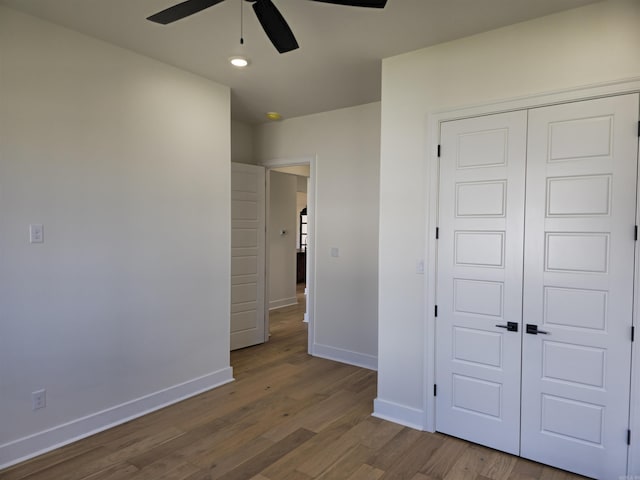 unfurnished bedroom with ceiling fan, a closet, and hardwood / wood-style flooring