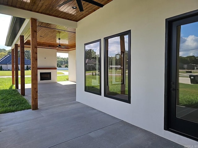 view of patio featuring ceiling fan and a large fireplace