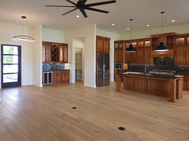 kitchen featuring pendant lighting, light wood-type flooring, backsplash, and appliances with stainless steel finishes