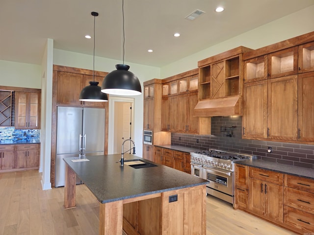 kitchen featuring backsplash, sink, a center island with sink, high quality appliances, and light hardwood / wood-style floors