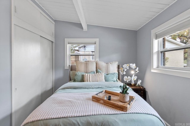 bedroom featuring multiple windows and vaulted ceiling with beams