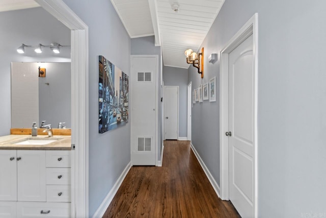 hallway featuring lofted ceiling with beams, wood ceiling, sink, and dark wood-type flooring